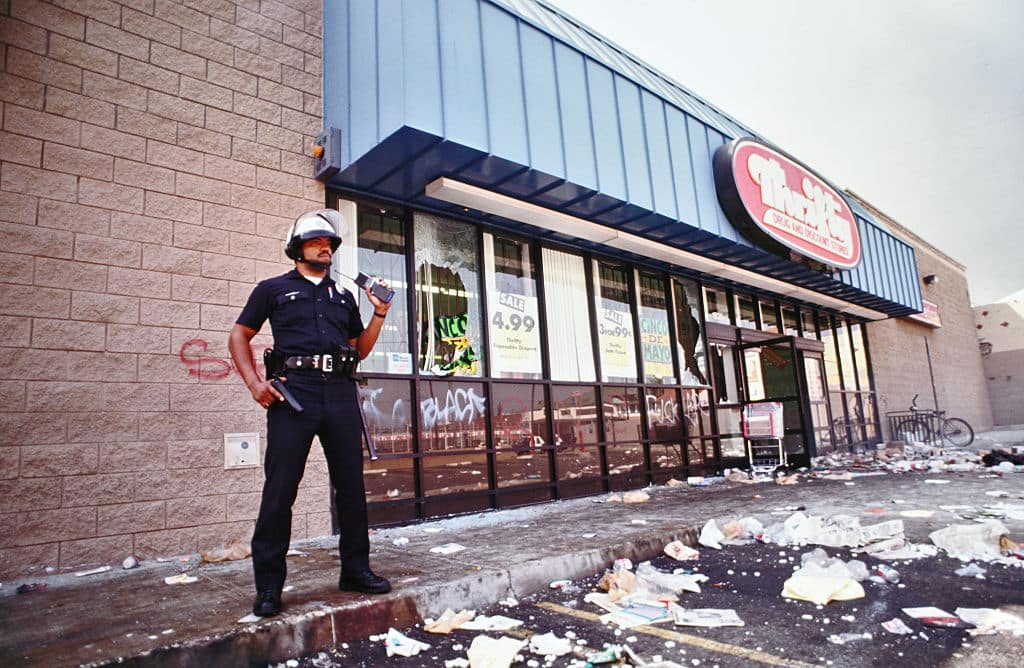 A lone LAPD officer keeps looters at bay from a Thrifty Drug and Discount store. Most of the store was cleaned out by looters. Los Angeles has undergone several days of rioting due to the acquittal of the LAPD officers who beat Rodney King. Hundreds of businesses were burned to the ground and over 55 people have been killed. (Photo by Ted Soqui/Corbis via Getty Images)