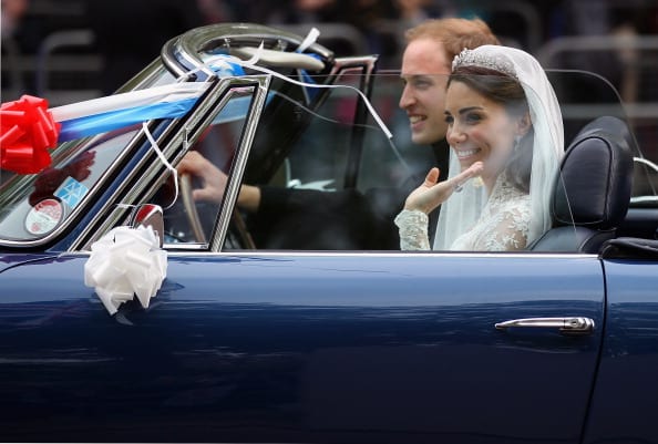 Prince William, Duke of Cambridge and Catherine, Duchess of Cambridge drive from Buckingham Palace to Clarence House in a decorated vintage Aston Martin sports car on April 29, 2011 in London, England. The marriage of the second in line to the British throne was led by the Archbishop of Canterbury and was attended by 1900 guests, including foreign Royal family members and heads of state. Thousands of well-wishers from around the world have also flocked to London to witness the spectacle and pageantry of the Royal Wedding (Photo by Jeff J Mitchell/Getty Images)