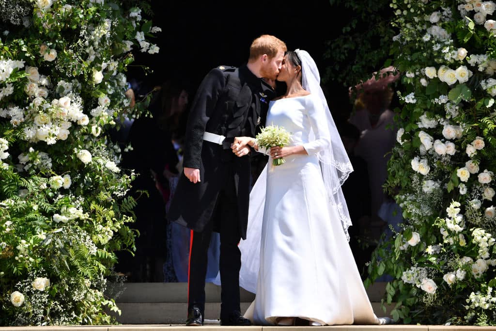 Britain's Prince Harry kisses his wife Meghan as they leave from the West Door of St George's Chapel, Windsor Castle on May 19, 2018 (Photo by Ben STANSALL - WPA Pool/Getty Images)