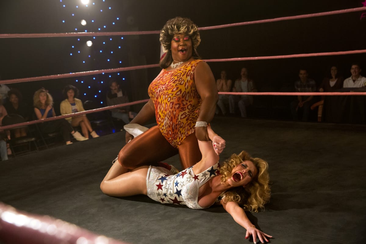 Kia Stevens who plays the Welfare Queen on 'GLOW' is a professional wrestler who appeared on Total Nonstop Action Wrestling under the ring name Awesome Kong. Pictured: Kia and Betty Gilpin, who portrays Liberty Belle (Netflix)