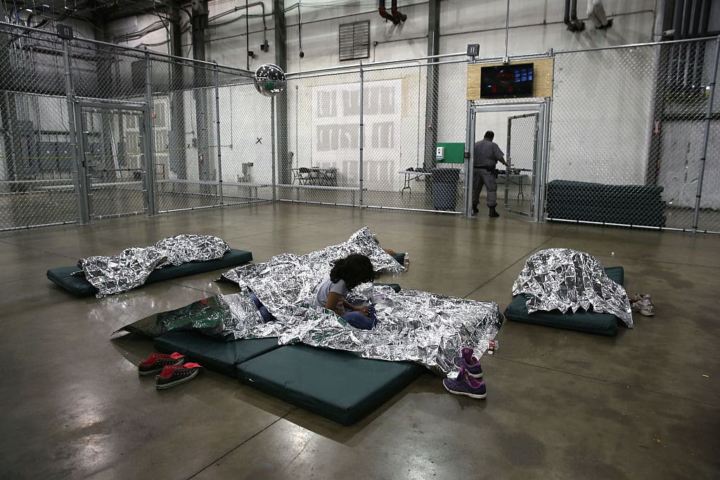 A girl from Central America rests on thermal blankets at a detention facility run by the U.S. Border Patrol on September 8, 2014, in McAllen, Texas. The Border Patrol opened the holding center to temporarily house the children after tens of thousands of families and unaccompanied minors from Central America crossed the border illegally into the United States during the spring and summer. (Photo by John Moore/Getty Images)