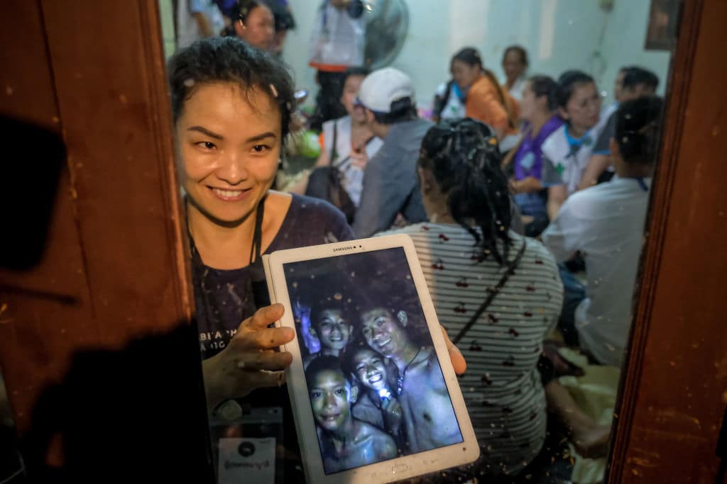 Relatives of the missing boys show photos of them after the 12 boys and their soccer coach have been found alive in the cave where they've been missing for over a week after monsoon rains blocked the main entrance on July 02, 2018 in Chiang Rai, Thailand. (Getty Images)