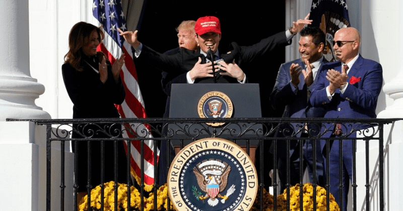 Trump hugs Washington Nationals catcher Kurt Suzuki from behind after he wears red MAGA cap to White House celebration
