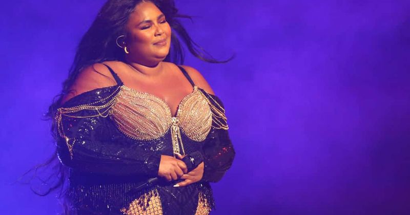 Lizzo dazzles in sparkling sexy leotard wrapped in festive red bow at iHeartRadio Jingle Ball concert