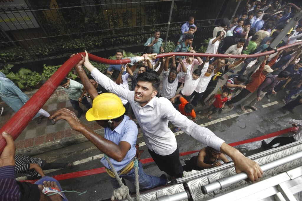 Locals help firefighters douse a fire in a multi-storied office building in Dhaka, Bangladesh, Thursday, March 28, 2019 (AP)