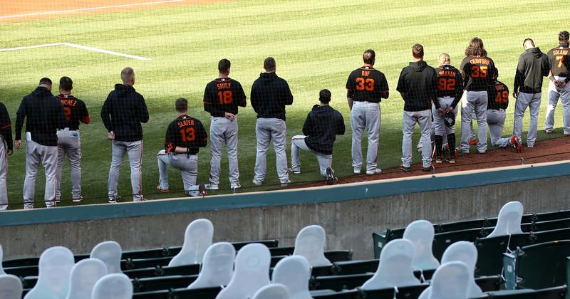 Giants manager Gabe Kapler kneels with players during national anthem before 6-2 victory over Oakland Athletics